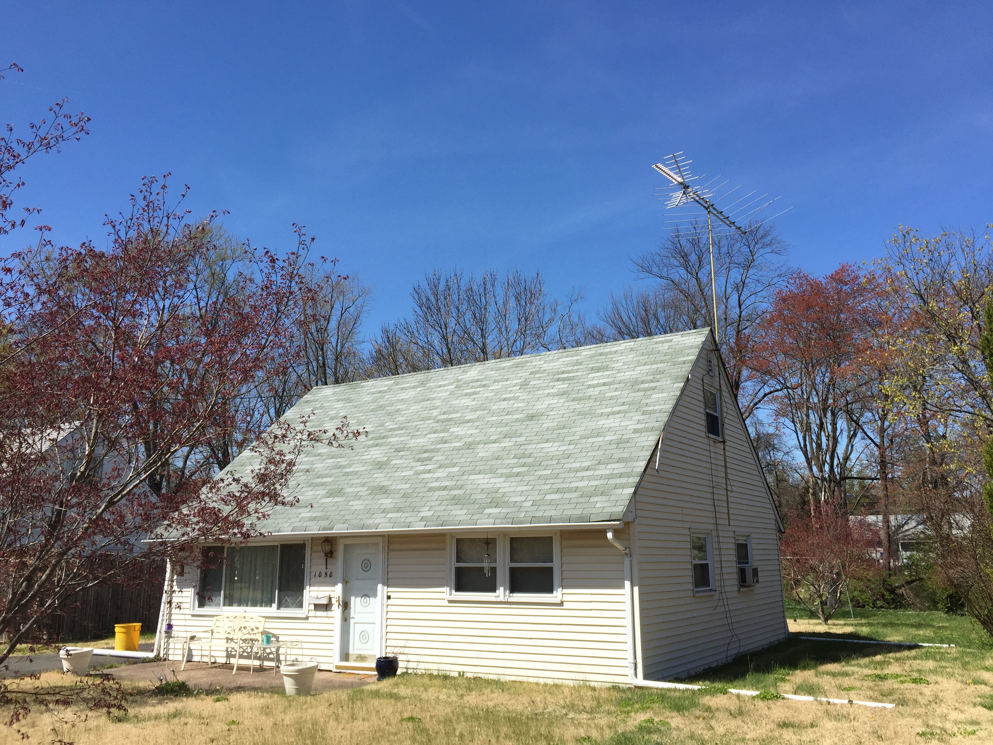 A modest New England Cape with a TV antenna and an as-is yard